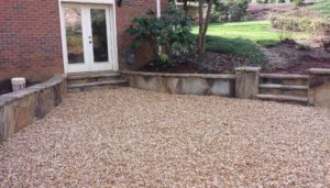 A patio with a stone wall and a brick wall.