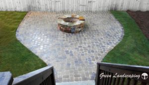 Backyard cobblestone patio with central stone firepit