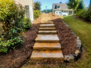 Stone steps with landscaping on both sides leading up a hill.
